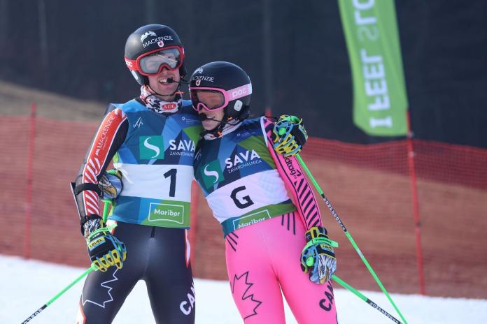 A male Para alpine skiing athlete and a female guide pose for a photograph after competition